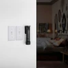Lampe de poche Olight Seeker 2 pro fixée au mur à côté d'interrupteurs, chambre à coucher sombre en arrière-plan.
