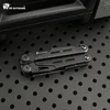 Pince multifonction noire HX Outdoors pliée sur une surface métallique perforée pour le camping et le bivouac.