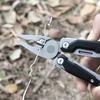 Pince coupante d'un outil multifonction sectionnant un fil métallique en extérieur.