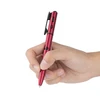 Olight Open 3 stylo-lampe de poche rouge en main, avec clip de poche, pour écriture et éclairage.