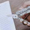 Main tenant une pince multifonction NexTool pour couper le coin d'une feuille de papier blanc ligné