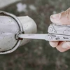 Utilisation de la lame d'un outil multifonction de poche pour réparer une pièce métallique.