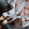 Pince multifonction NexTool utilisée pour serrer un écrou rouillé sur un vélo lors d'une réparation mécanique.