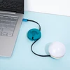 Lampe sphérique blanche et ordinateur portable reliés par câble USB Olight avec organisateur de câbles turquoise.