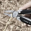 Coupe-fil de la pince multifonction NexTool W40 sectionnant un câble électrique jaune en extérieur.