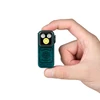 Mini lampe de poche rechargeable Olight verte gravée boussole tenue entre deux doigts sur fond blanc.