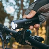 Main gantée installant phare de vélo Olight allumé sur le guidon.