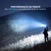 Lampe torche puissante de 2300 lumens éclairant une forêt la nuit lors d'une randonnée nocturne.