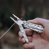 Pince coupe-fil du couteau multifonction NexTool tenue à la main pour sectionner un câble métallique en extérieur