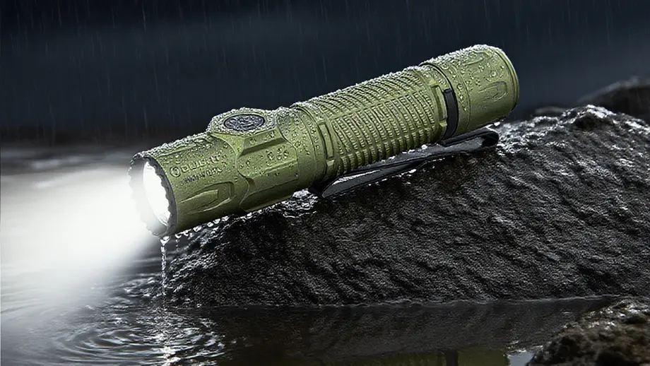 Torche Olight verte étanche, son faisceau illumine l'eau sous la pluie sur roche.