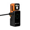 Lampe torche Olight orange sur son boîtier de charge noir avec câble USB branché et indicateur de batterie vert.