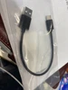 Câble USB noir (USB-A vers USB-C) sous emballage plastique transparent.
