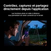 Homme dans une tente, contrôlant une caméra thermique sur trépied avec un smartphone. Appli de vision nocturne.