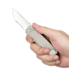 Couteau de poche EDC pliant avec lampe LED intégrée tenu en main, manche beige et lame tanto sur fond noir