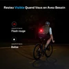 Cycliste de nuit équipé d'un feu arrière rouge clignotant de sécurité sur son maillot pour rester visible.