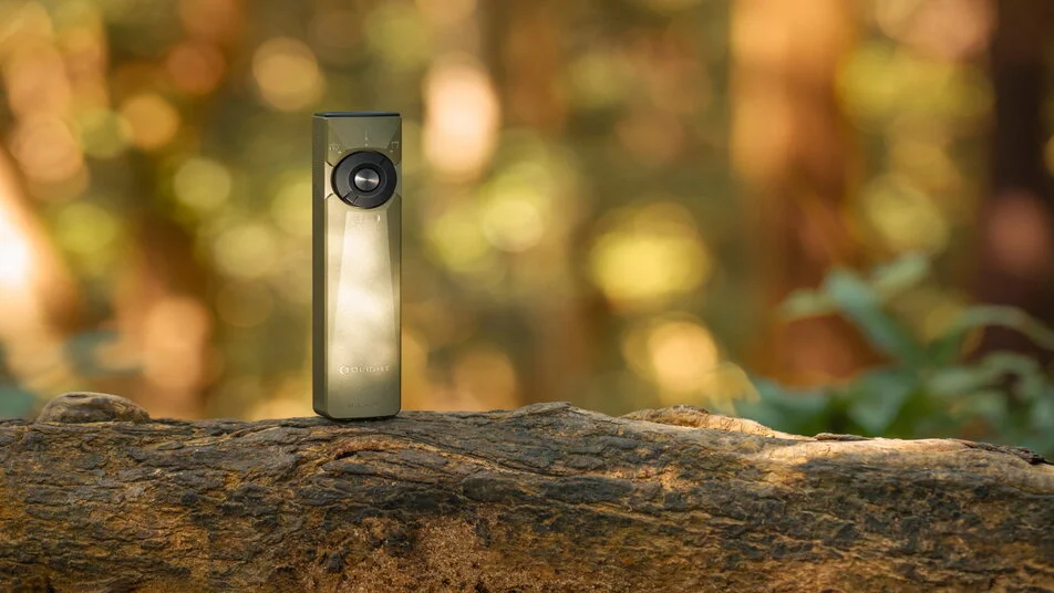 Lampe torche Olight vert olive sur un tronc d'arbre en nature.