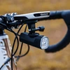 Appareil Garmin et phare de vélo fixés sur un support de guidon de vélo.