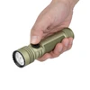 Main tenant une lampe de poche Olight Seeker Ultra vert kaki avec le pouce sur le bouton d'alimentation